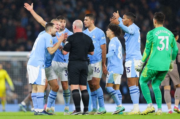 Referee Simon Hooper is surrounded by Erling Haaland, Rodri, Rico Lewis, Ederson, Mateo Kovačić and Rúben Dias of Manchester City after he stopped the game to award Manchester City a free kick and deny Jack Grealish (not pictured) the chance to play on and have a goal scoring chance during the Premier League match between Manchester City and Tottenham Hotspur at Etihad Stadium on December 03, 2023 in Manchester, England.